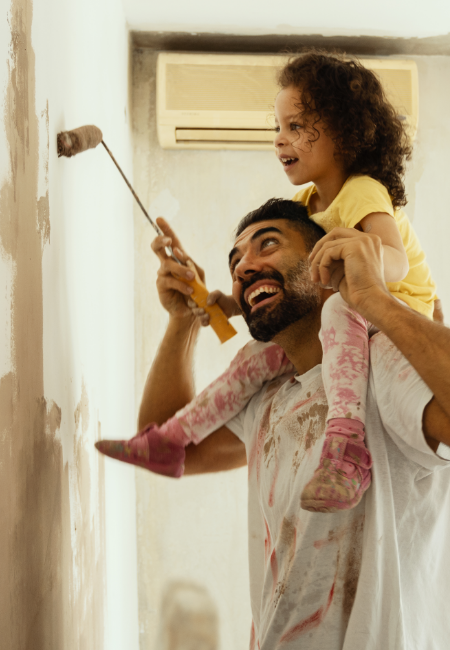 Father and young daughter paint a wall in their new home