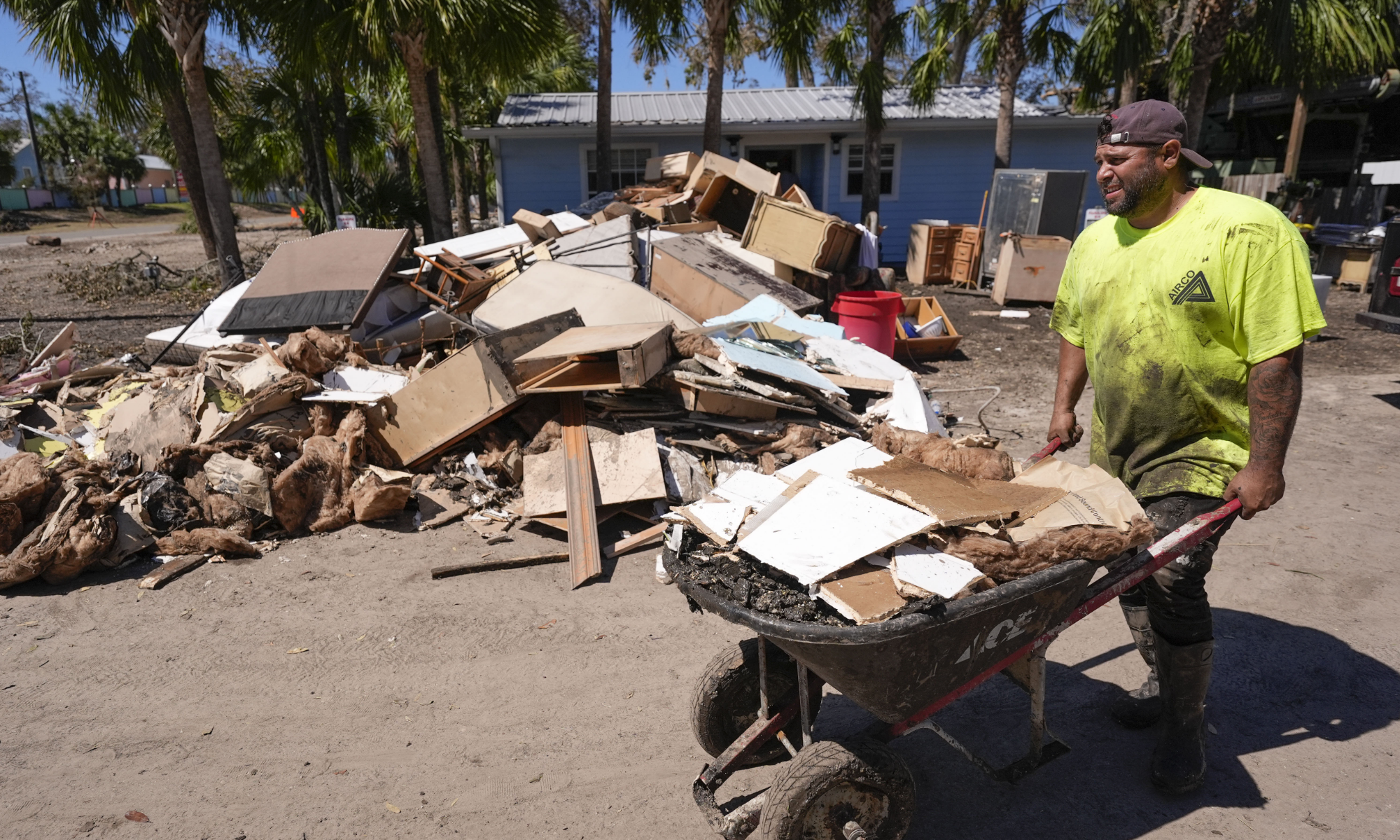 Jose Salazar dumps debris as he helps gut a property that took on a storm surge in the aftermath of Hurricane Helene, in Steinhatchee, Fla., Sunday, Sept. 29, 2024. (AP Photo/Gerald Herbert)