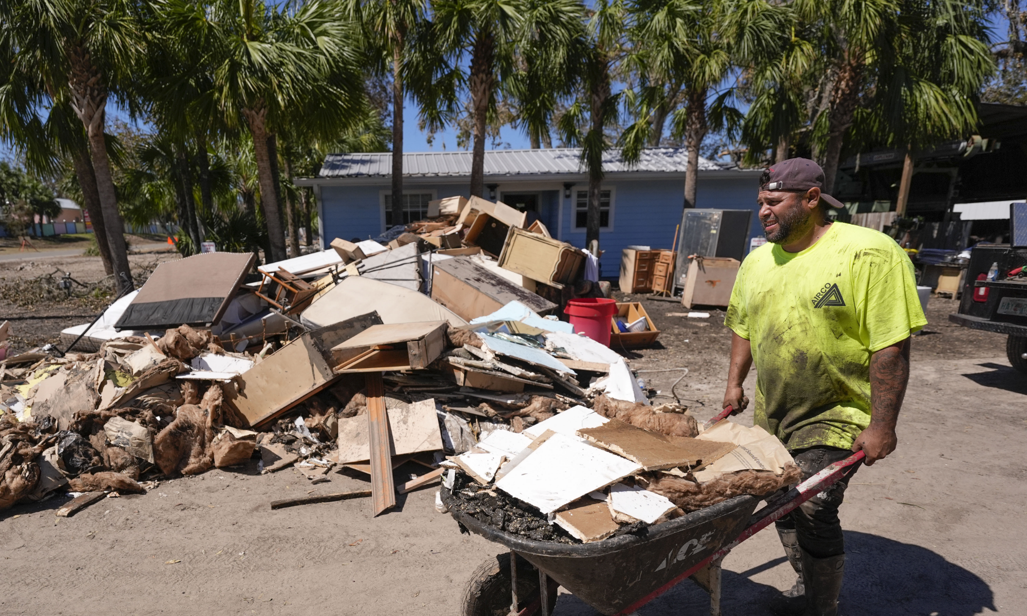 Jose Salazar dumps debris as he helps gut a property that took on a storm surge in the aftermath of Hurricane Helene, in Steinhatchee, Fla., Sunday, Sept. 29, 2024. (AP Photo/Gerald Herbert)