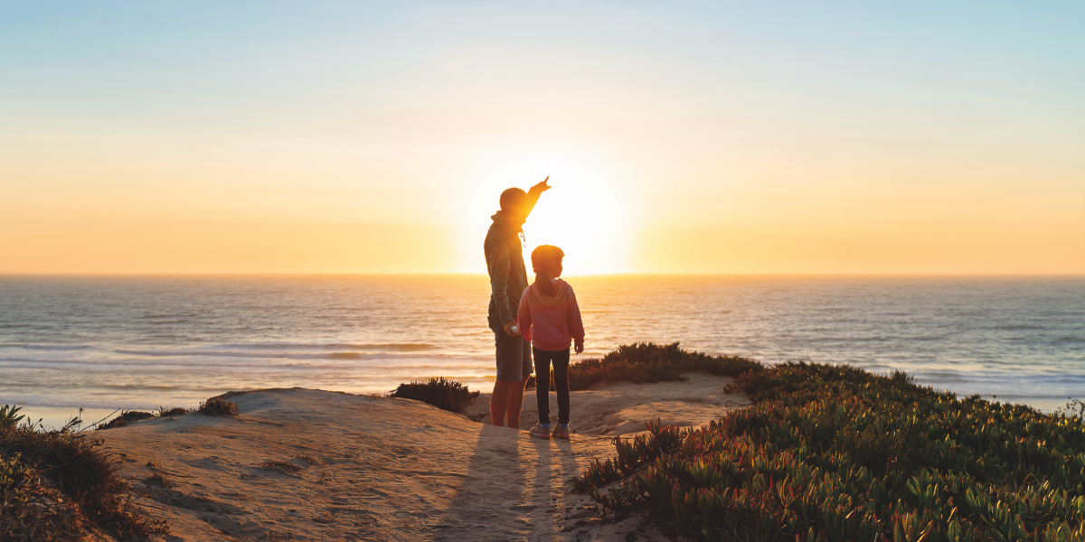 Adult and child on a cliff by the water